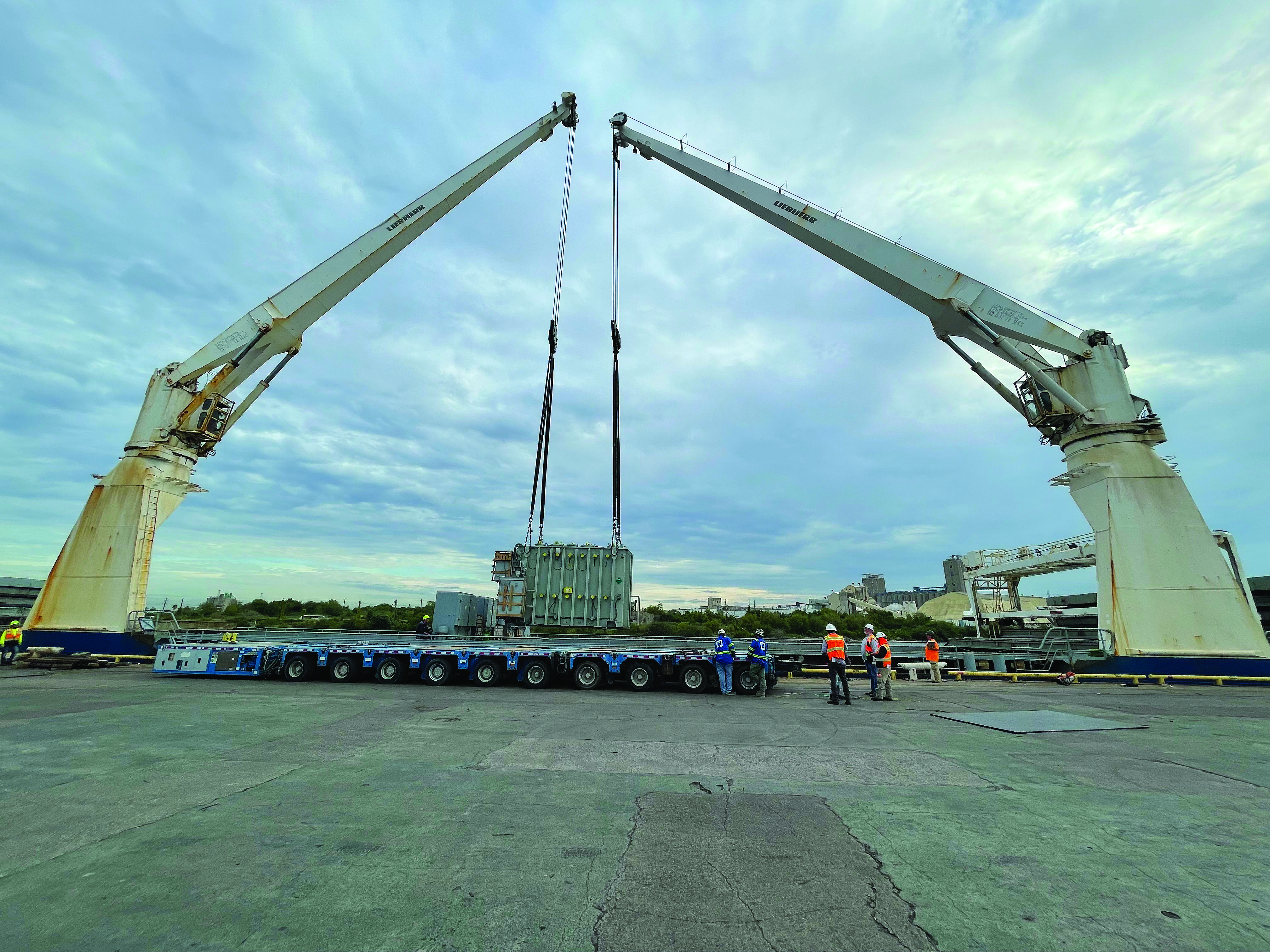Cranes lowering transformer onto cargo ship